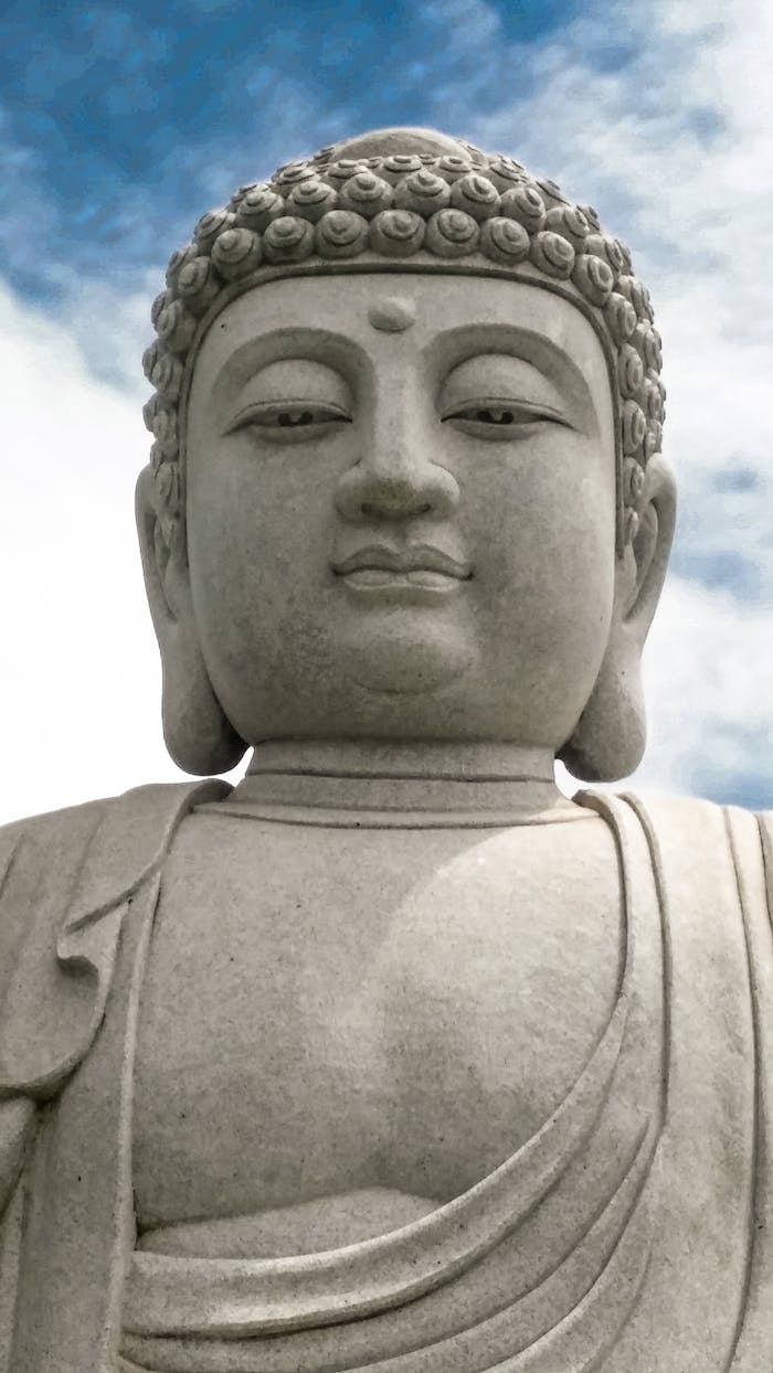 Close-up of a grand stone Buddha statue with a serene expression against a blue sky.